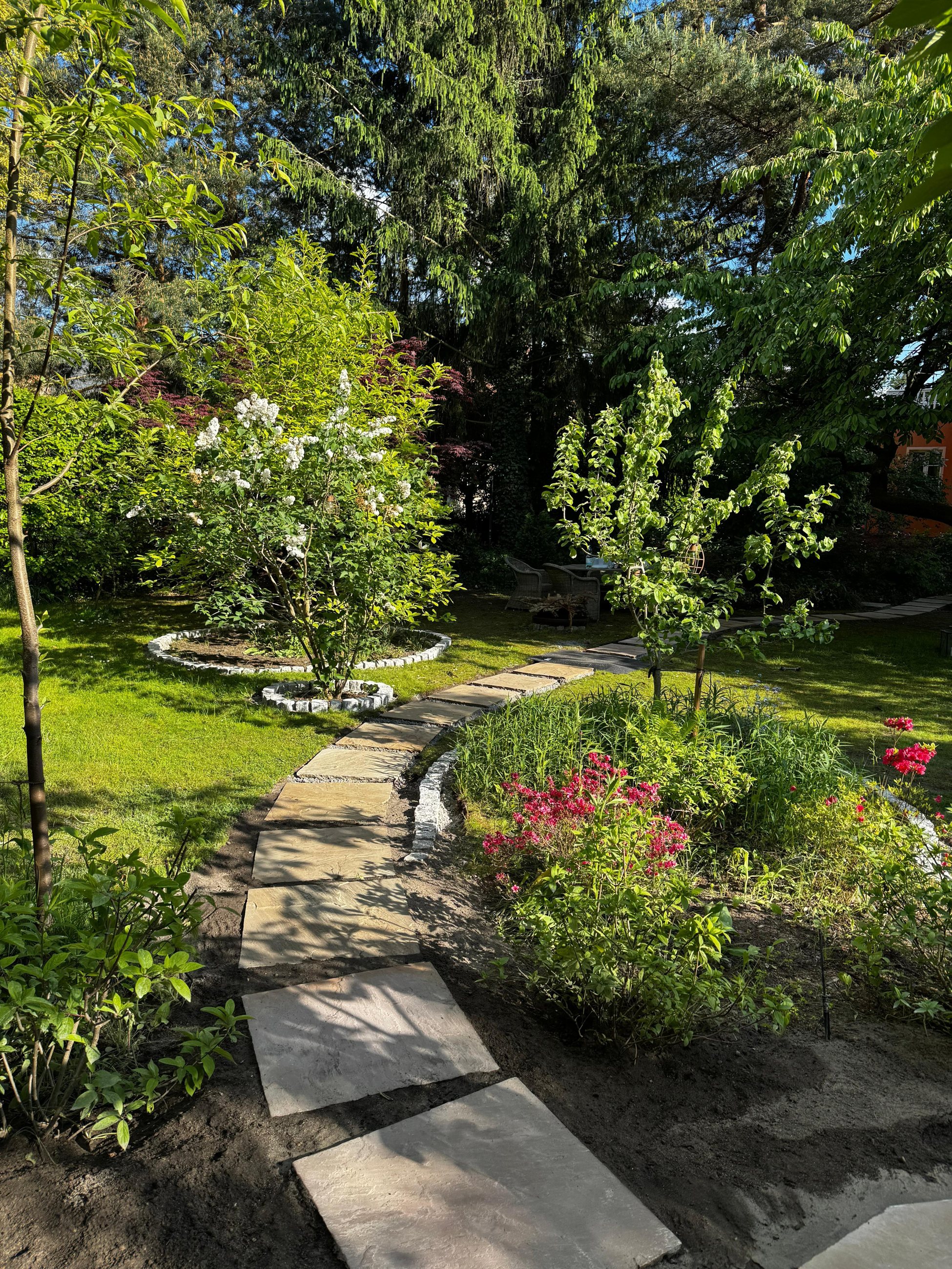 Gepflegter Privatgarten mit Natursteinweg, Rasen und blühenden Beeten, eine Referenz von Hauptstadt Gartenpflege