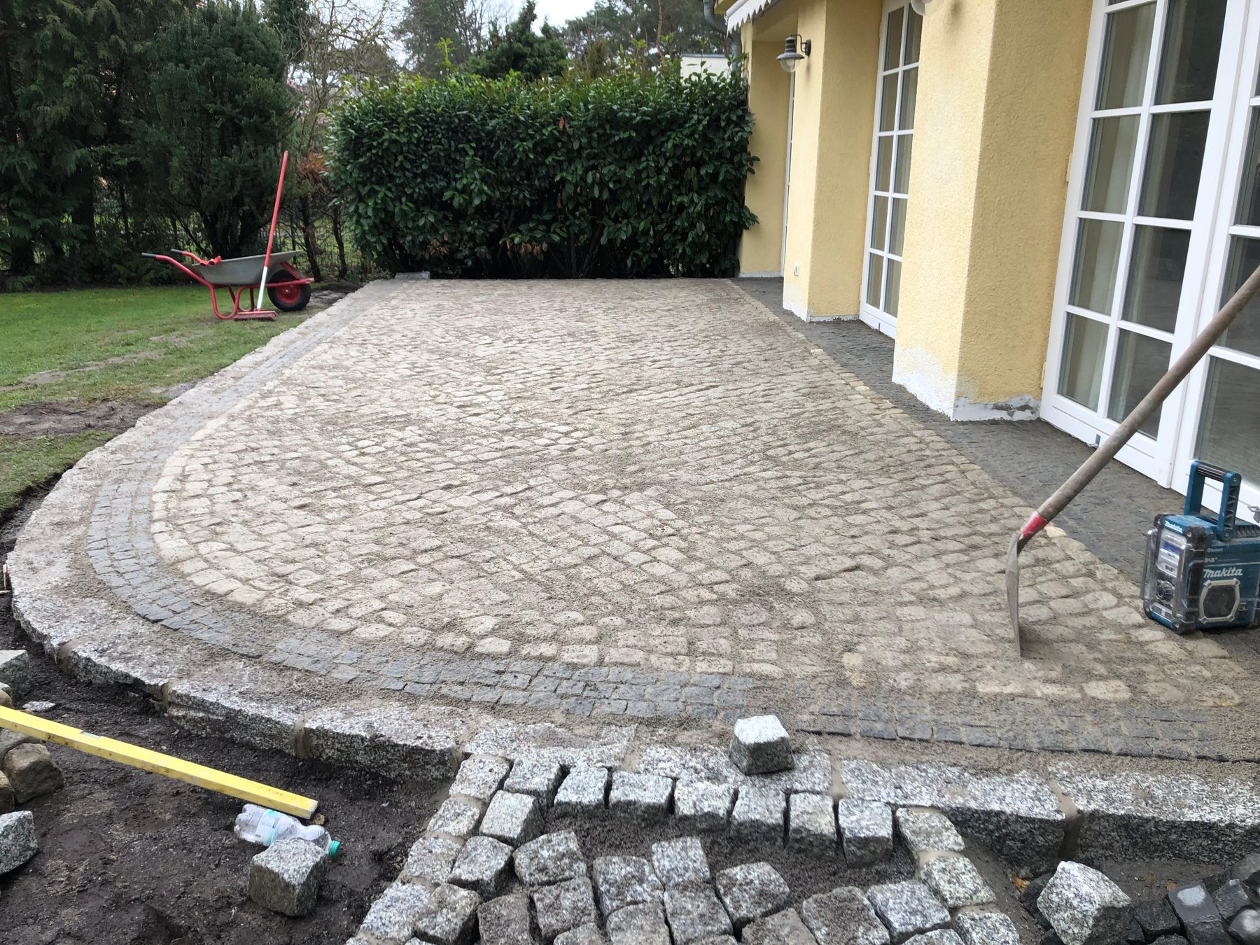 Echtes Kundenprojekt: halbrunde Terrasse aus Granit-Kleinpflaster während der Verlegung